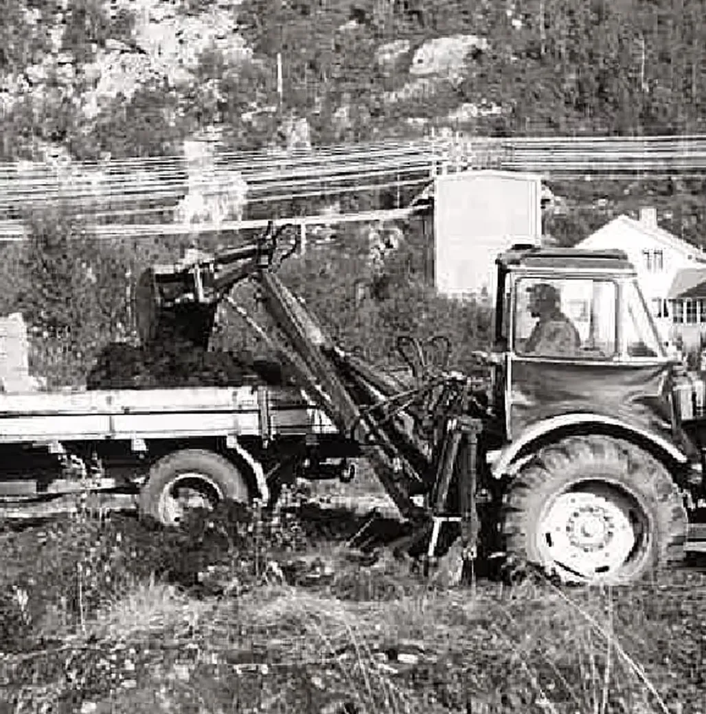 Traktorgraver som laster masse på en lastebil