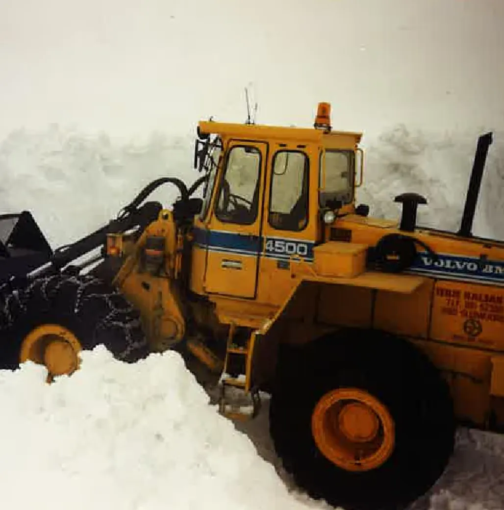 Gul Volvo hjullaster som brøyter snø