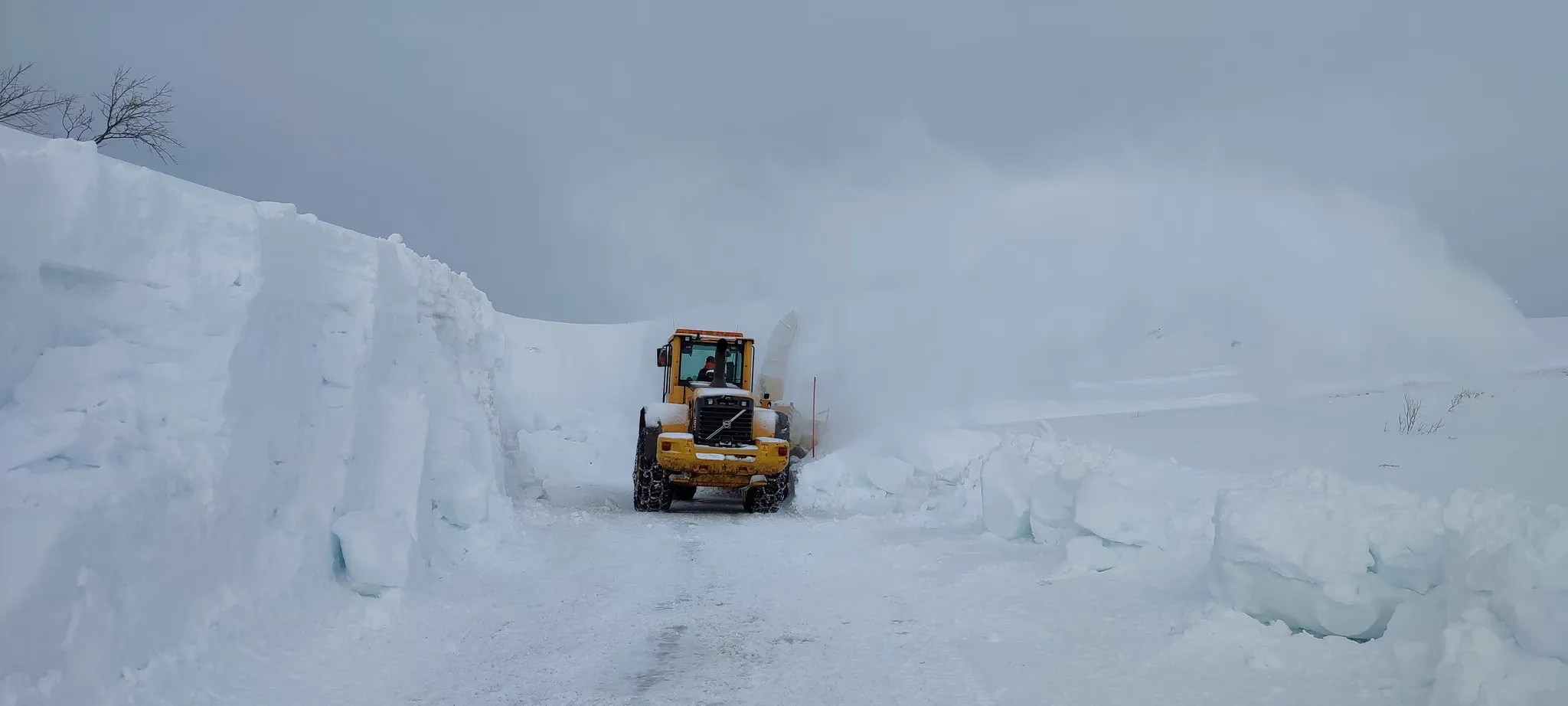 Hjullaster med snøfreser som åpner en vei mellom høye snøkanter