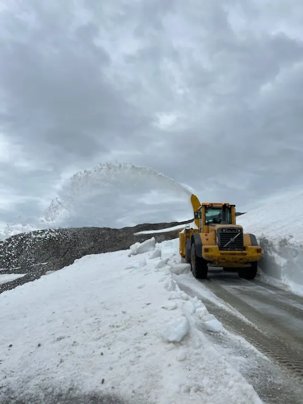 Hjullaster med snøfreser som freser snø langs en fjellvei