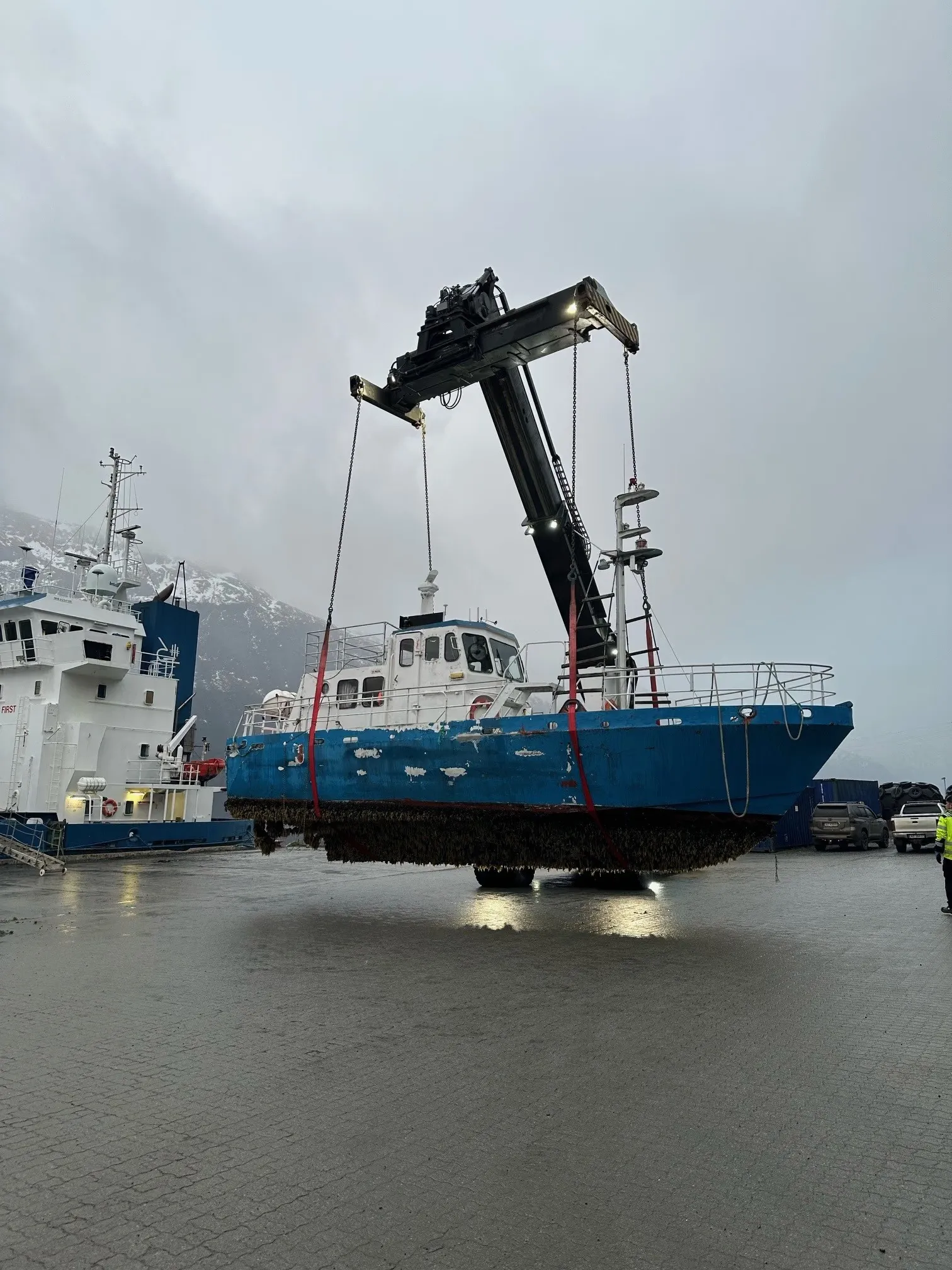 Båt som løftes på land av en stor truck på en kai
